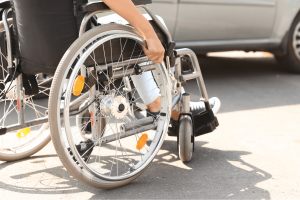 personne en fauteuil roulant devant une voiture adaptée au transport de personne à mobilité réduite